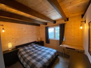 ein Schlafzimmer mit einem Bett in einer Holzhütte in der Unterkunft Chalet au coeur des montagnes in LʼAnse-Saint-Jean