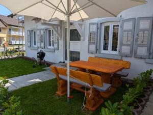 a table and bench under an umbrella in a yard at Ferienwohnung Malea max 4 Personen ca 60m2 in Bermatingen