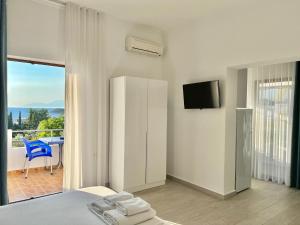 a bedroom with a bed and a television and a balcony at Dine Hotel in Ksamil