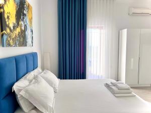 a bedroom with a bed with a blue headboard at Dine Hotel in Ksamil