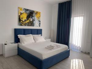 a bed with a blue headboard in a bedroom at Dine Hotel in Ksamil