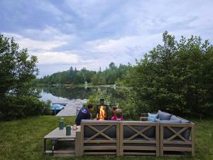 a group of people sitting around a table with a fire at Le Lac Apaisant - Rustic Haven by the Water in Saint-Calixte +27 photos