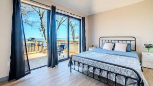2-bedroom Lake Front Cottage in Harwood ON #4 في Harwood: غرفة نوم مع سرير وشرفة