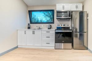 Una cocina con gabinetes blancos y un refrigerador de acero inoxidable. en 2-bedroom Lake Front Cottage in Harwood ON #4, en Harwood