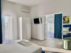 a white bedroom with a bed and a television at Dine Hotel in Ksamil