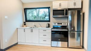 a kitchen with white cabinets and a stainless steel refrigerator at 2-bedroom Lake Front Cottage in Harwood ON #7 in Harwood +28 photos