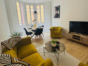 a living room with a yellow couch and a table at Chez Rose Appartement cosy centre ville in Vichy