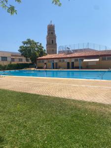 a building with a swimming pool with a clock tower at Manzaneque Rural House in Caudete de las Fuentes