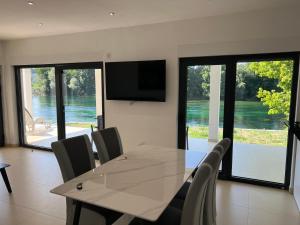 a dining room with a table with chairs and a television at Apartmani na Uni Šarac in Otave