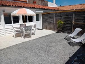 a patio with a table and chairs and an umbrella at Maison proche centre-ville et baignade in L'Aiguillon-la-Presqu'île