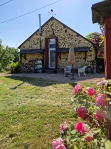 Een buitenaanzicht van een stenen gebouw met een parasol en rozen. bij Gîte La Sarrée in Onlay +20 foto's