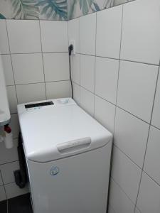 a white refrigerator in a kitchen with white tiles at Maison proche centre-ville et baignade in L'Aiguillon-la-Presqu'île +11 photos