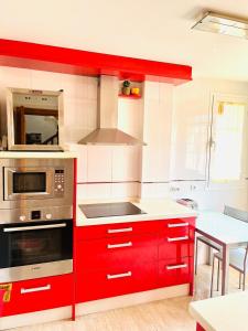 a kitchen with red cabinets and a stove at Sol y Relax en tu Chalet Pareado in Aguadulce