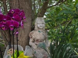 a statue sitting next to a tree with flowers at Villa Sette Nani in Torre Lapillo