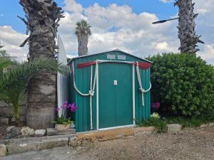 a green outhouse with a palm tree in the background at Villa Sette Nani in Torre Lapillo