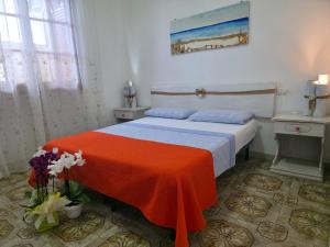 a bedroom with a bed with an orange blanket on it at Villa Sette Nani in Torre Lapillo