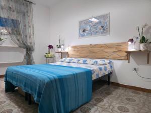 a bedroom with a bed with a blue blanket on it at Villa Sette Nani in Torre Lapillo