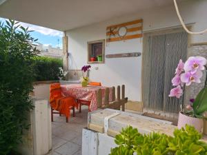 a patio with a table and chairs and flowers at Villa Sette Nani in Torre Lapillo