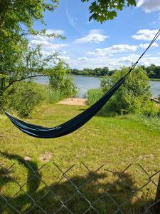 a hammock hanging from a fence next to a lake at Na Spontanie in Sąpłaty