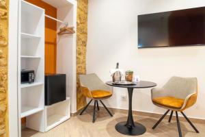 a room with a table and two chairs and a tv at Corte Atenea Guest House Experience & Spa in Agrigento