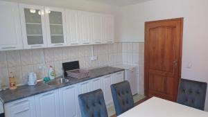 a kitchen with white cabinets and a table and chairs at Apartment Merak II in Sarajevo