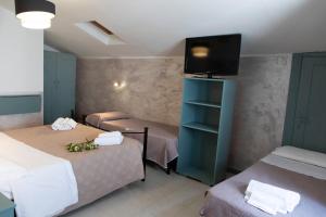 a room with two beds and a flat screen tv at Hotel Il Vicoletto in Assisi
