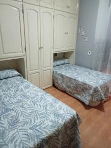 two beds in a room with white cabinets at Piso mar in Salobreña