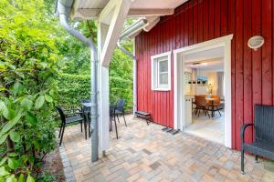 a red house with a patio with chairs and a table at Dünenhaus Ückeritz UnserUsedomDe FeWo ca40qm mit Parkplatz direkt am Strand 6I2 in Ueckeritz
