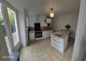 a kitchen with white cabinets and a large window at Logement Douce évasion in Saint-Julien-lʼArs
