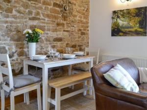 un tavolo e delle sedie con un tavolo bianco e un muro di mattoni di Stanegate Cottage a Greenhead