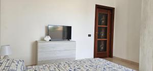 une chambre avec un lit et une télévision sur une commode dans l'établissement La Loggia sul mare, à Tarente
