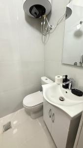 a white bathroom with a toilet and a sink at Ora Appartments in Shkodër +12 photos
