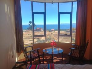 a room with a table and chairs in front of a window at Luquina homestay in Puno