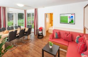 a living room with a red couch and a table at Landhaus Anni in Saalbach-Hinterglemm