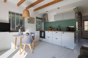 a kitchen with white cabinets and a table at Vakantiehuisje Grijpskerke, hartje Walcheren in Grijpskerke