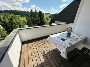 a wooden deck with a table on a balcony at Haus - Sonneck in Schonwald im Schwarzwald