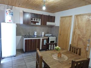 a kitchen with a wooden table and a refrigerator at Cabañas Elohim in El manzano historico