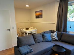 a living room with a blue couch and a table at Vier Nordlichter Erdgeschosswohnung mit Terrasse und Garten in Bensersiel