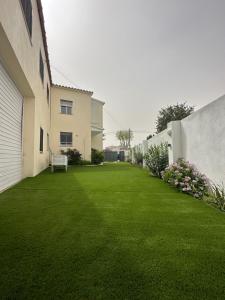 a yard with green grass and flowers next to a building at REQUESENS Playa in Empuriabrava +71 photos