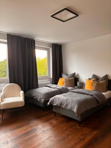 a bedroom with two beds and a chair and two windows at Wohnen am Hansaplatz in Wolfsburg