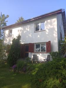 a white house with two chairs in a yard at Apartament u Romana, in Tałty +5 photos