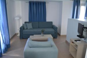 a living room with a blue couch and a table at Atrium Villa in Fira