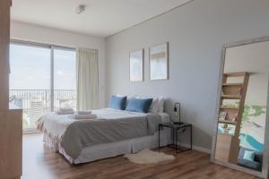 Un dormitorio blanco con una cama grande con almohadas azules. en MOT Azopardo 700 'A' - Lux Lofts Puerto Madero, en Buenos Aires