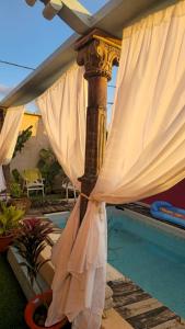 a pole with a white curtain next to a pool at פלא - PELEH -KASHMIR -Quiet place 3 km from caesarea beach in Or ‘Aqīvāh