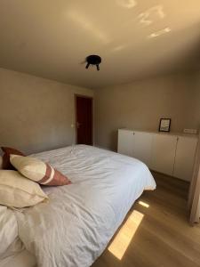 a bedroom with a large white bed with a person laying on it at Ruim, stijlvol gerenoveerd vakantieappartement voor 4 personen vlak bij zee en de duinen in De Panne