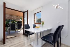 a dining room with a white table and black chairs at Apartment Mija with garden in Kornić +10 photos