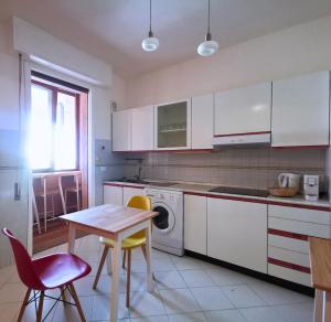 a kitchen with white cabinets and a table and chairs at GuestHouse dei Fiori - Hituscany in Pisa
