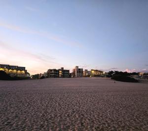 a sandy beach with buildings in the background at Puerto Encuentro in Mar Azul