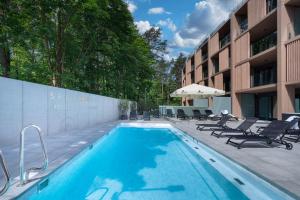 a swimming pool with chairs and a building at Eden Sea in Międzyzdroje