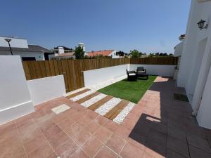 un patio avec un banc et de l'herbe dans une cour arrière dans l'établissement Sanbia - Comporta Beach House, à Carvalhal